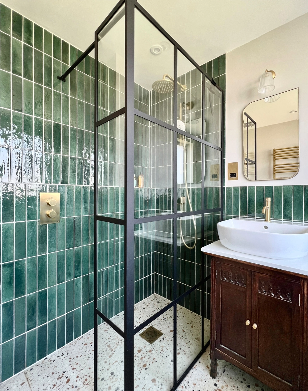 Eclectic bathroom with wetroom style shower in dark emerald green and terrazzo tiles and vintage cupboard turned vanity
