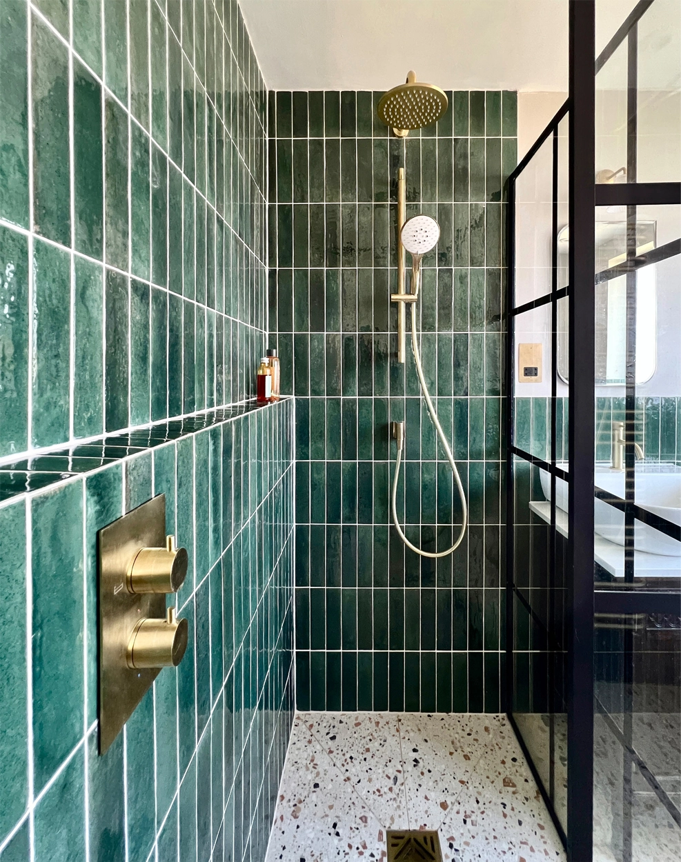 Eclectic bathroom with wetroom style shower with ledge tiled using in dark emerald green brick tiles and terrazzo tiles