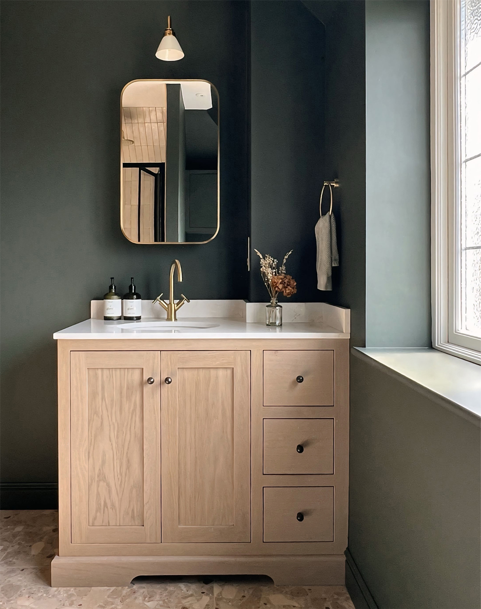Dark green ensuite shower room bathroom with custom oak basin vanity and terrazzo floor - design by First Sense Interiors